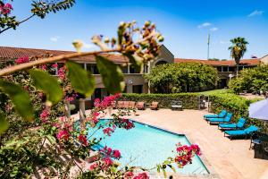 a resort with a swimming pool with chairs and flowers at Vineyard Court Designer Suites Hotel in College Station