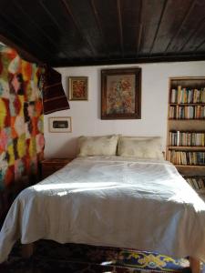 a bedroom with a white bed and a book shelf at Къщата на художника in Zheravna