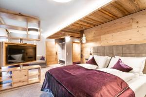 ein Schlafzimmer mit einem großen Bett und einem Flachbildfernseher in der Unterkunft Der Postwirt in Söll + 94 Fotos