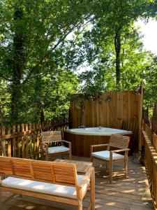 a wooden deck with two benches and a table at Magic Roof Top Bus with big bath in the tree forest! in Mimizan