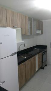 eine Küche mit einem weißen Kühlschrank und Holzschränken in der Unterkunft OneFlat in João Pessoa