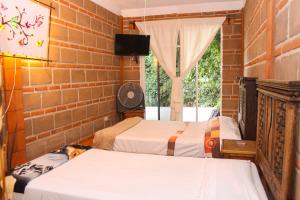 duas camas num quarto com uma parede de tijolos em Hospedaje Piedra de Sol em Tepoztlán