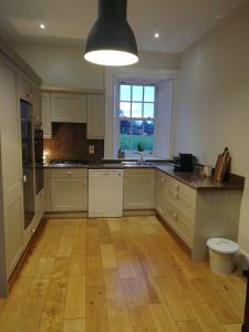 a kitchen with white cabinets and a wooden floor at Next door at Broomfield House in Midleton