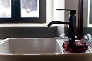 a bathroom sink with a faucet and a red glass at Proprietà Scalfati in Sabaudia +55 photos