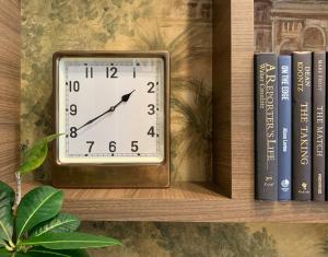 a clock sitting on a shelf with books at The Dylan Hotel at SFO in Millbrae