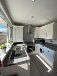 una cocina con armarios blancos y fregadero en COLERIDGE LODGE, en Thornton