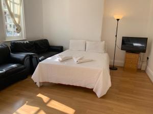 Un dormitorio con una cama blanca y un televisor. en Brick lane stay, en Londres