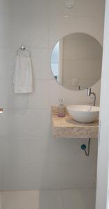 uma casa de banho branca com um lavatório e um espelho em Loft para temporada em Cabo Frio