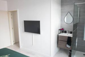 a bathroom with a sink and a tv on a wall at Le natural'appart des 3 frontières in Village-Neuf