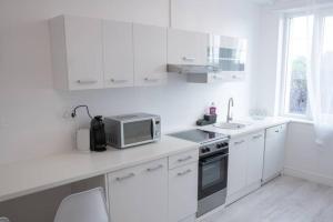 a white kitchen with a microwave and a sink at Le natural'appart des 3 frontières in Village-Neuf