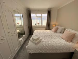 a bedroom with a bed with white sheets and a mirror at COLERIDGE LODGE in Thornton