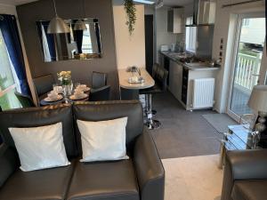 a living room with a leather couch and a table at Lola Lodge - Luxury Hot Tub Retreat in Newton on the Moor