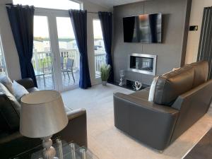 a living room with a couch and a tv at Lola Lodge - Luxury Hot Tub Retreat in Newton on the Moor