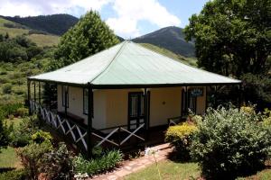 a small house with a green roof in a garden at The Royal Hotel Pilgrims Rest in Pilgrim's Rest