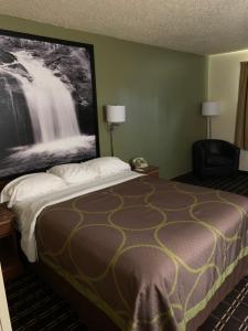 a hotel room with a bed with a large picture on the wall at Super 8 by Wyndham Watertown WI in Watertown