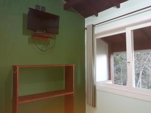 a living room with a flat screen tv and a window at Pousada do Horto in Trindade