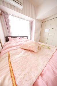 a large pink bed in a room with a window at Du Etowaaru in Nagoya