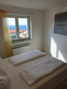 two beds in a white room with a window at Guest House Mare e Monti in Rabac