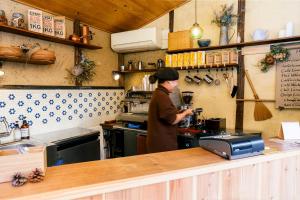 a woman standing in a kitchen preparing food at Guest house Roji to Akari in Naoshima