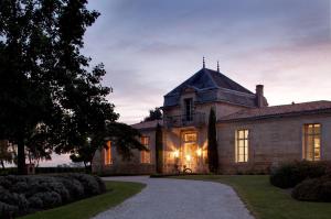 une ancienne maison en pierre avec une tourelle et une allée. dans l'établissement Château Cordeillan-Bages, à Pauillac