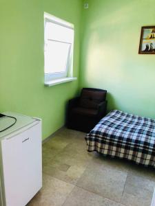 a room with a bed and a chair and a window at Villa Diana Mini in Karolino-Buhaz