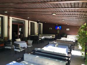a patio with tables and chairs and a tv on a ceiling at Hotel boutique Garden Resort by Brancoveanu in Moieciu de Jos