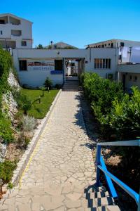 a pathway leading to a building with a blue bench at Beach Hotel in Drasnice