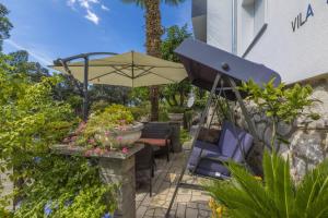 - une terrasse avec des chaises, un parasol et des fleurs dans l'établissement ZUPAN, à Crikvenica