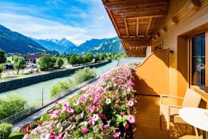 a balcony with a view of a river and flowers at Hotel Englhof in Zell am Ziller