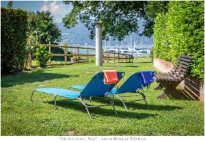 three lawn chairs and a bench in the grass at The Gulf Villa - Lago Maggiore in  Monvalle 