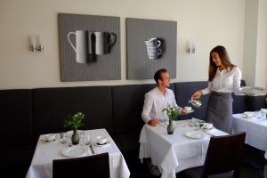 a woman serving a man at a table in a restaurant at Hotel An der Gruga in Essen