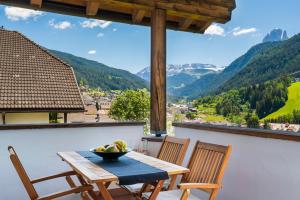 a table and chairs on a balcony with a bowl of fruit at Dolomites Chalet Niuasi in Ortisei