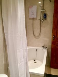 a white shower curtain in a bathroom with a tub at Yairbrig Holiday in Galashiels