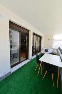 a living room with a table and chairs and green carpet at Apartamento CERCA PLAYA CON BALCON Y BBQ in Calafell