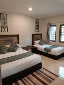 a hotel room with two beds and two windows at The Temak Villa in Pantai Cenang