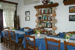 a restaurant with blue tables and chairs and a book shelf at Pension Akropolis in Kyra Panagia