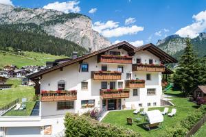 a large white building with balconies in the mountains at Residence Cesa Rives in Selva di Val Gardena