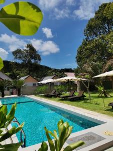 una piscina con sillas y sombrillas en un patio en The Temak Villa en Pantai Cenang