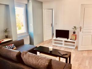 a living room with a couch and a tv at Apprt calme 2 chambres, proche thermes et centre ville, parking gratuit in Lons-le-Saunier