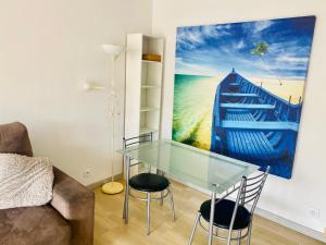 ジュアン・レ・パンにあるStudio avec piscine 100m plagesのリビングルーム(ガラスのテーブル、椅子付)