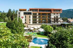 a hotel with a pool in front of a building at Hotel Olympia in Brunico