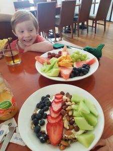 洛坎普頓的住宿－麗晶羅克漢普頓品質酒店，坐在桌子上的小女孩,吃两盘食物