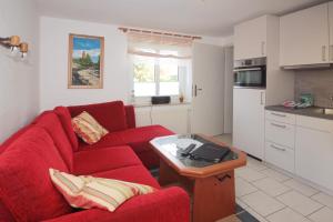 a living room with a red couch and a kitchen at Ferienwohnungen Thorsten Fründt in Prerow