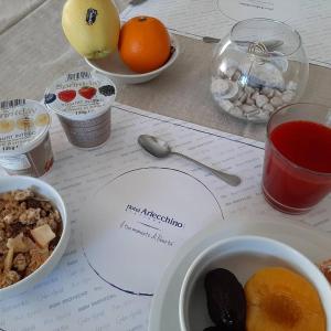 Hotel Arlecchino Riccione في ريتشيوني: طاولة مع طبق من الطعام وأوعية من الفواكه