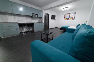 ein Wohnzimmer mit einem blauen Sofa und einer Küche in der Unterkunft Aviator Apartament - Business Class Confort - Luxury in Deva