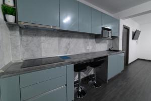 una cocina con armarios azules y una barra con taburetes en Aviator Apartament Alpha, en Deva