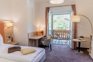 a hotel room with a bed and a desk and a window at Wohlfühlhotel Goiserer Mühle in Bad Goisern