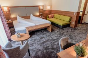 ein Hotelzimmer mit einem Bett, einem Sofa und Tischen in der Unterkunft Wohlfühlhotel Goiserer Mühle in Bad Goisern