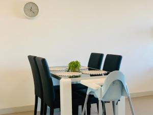 a dining room table with black chairs and a clock at Beautiful Home close to Shopping Mall and Train Hornsby in Hornsby
