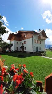 a house with a green yard with red flowers at Agritur Rizzi di Inama Ugo in Coredo